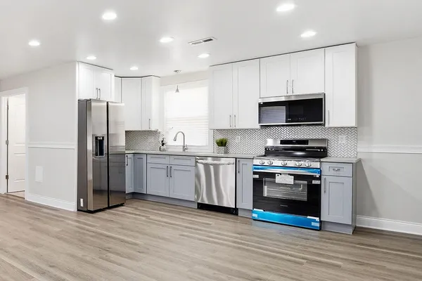 a kitchen with stainless steel appliances a stove a microwave and white cabinets