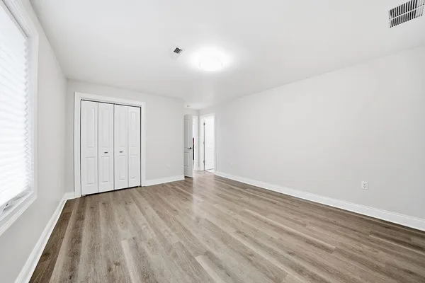 a view of an empty room with wooden floor and a window