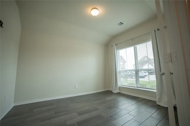 an empty room with wooden floor and windows