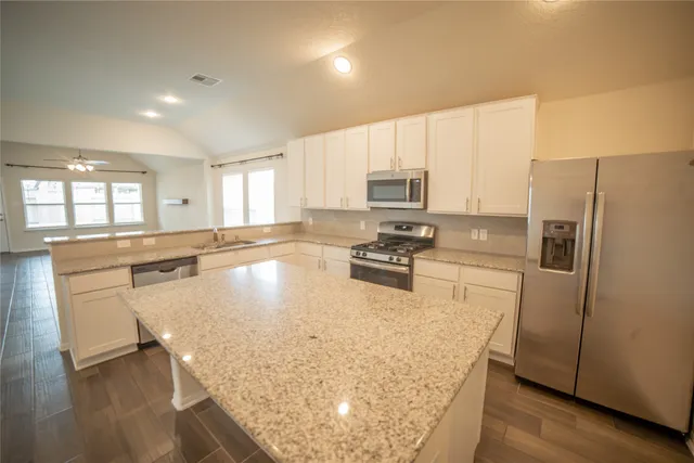 a kitchen with stainless steel appliances granite countertop a refrigerator a stove top oven a sink and dishwasher
