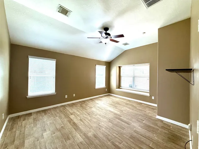 a view of an empty room with a window and wooden floor