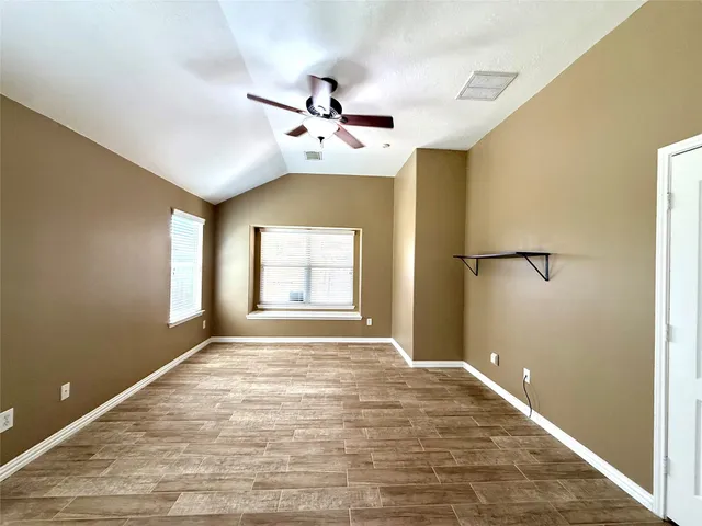 a view of an empty room with window and chandelier fan