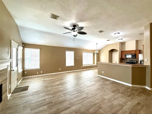 a view of an empty room with window and wooden floor