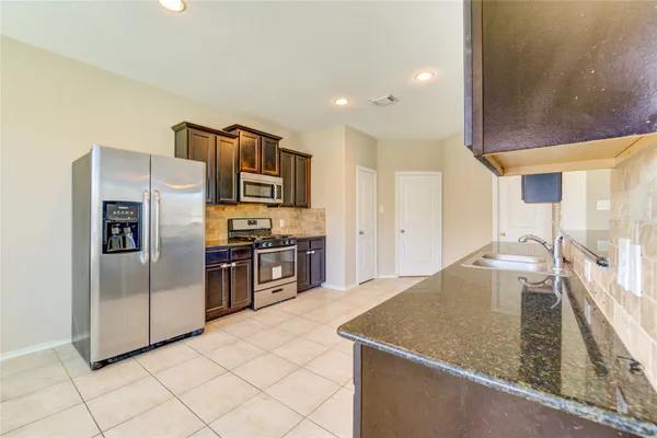 a kitchen with stainless steel appliances granite countertop a sink a microwave and a refrigerator