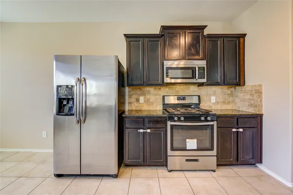 a kitchen with stainless steel appliances granite countertop a stove microwave and refrigerator