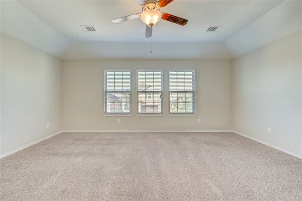 an empty room with chandelier fan and windows