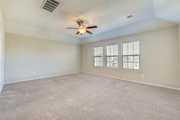 an empty room with windows and ceiling fan