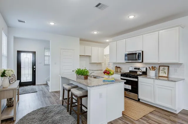 a kitchen with microwave a stove and cabinets