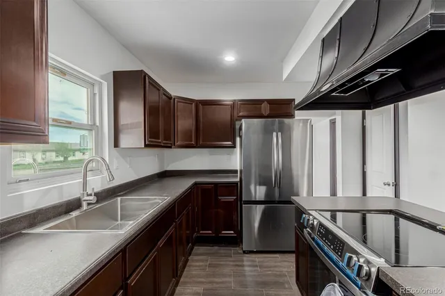 a kitchen with granite countertop a sink a stove and a refrigerator