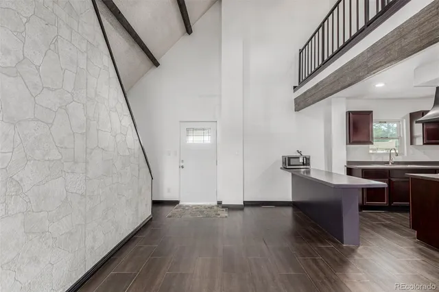 a living room with couches and kitchen view with wooden floor