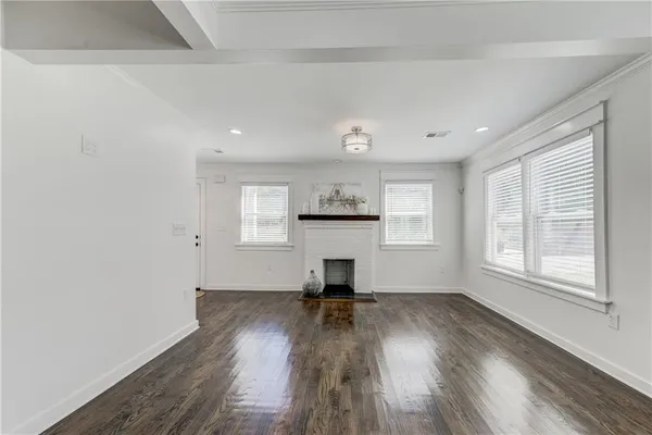 an empty room with wooden floor a fireplace and windows