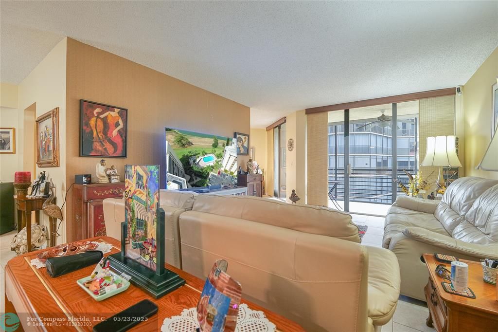 7300 Radice Court, Unit 302 Lauderhill, FL 33319 - Photo 7 of 81 a living room with furniture a flat screen tv and a floor to ceiling window