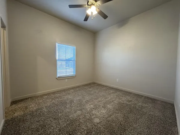 an empty room with a chandelier fan and windows