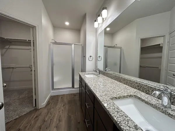 a bathroom with a granite countertop double vanity sink and mirror