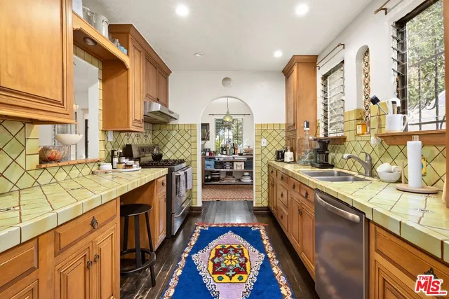 a large kitchen with stainless steel appliances granite countertop a large stove a sink and a large window