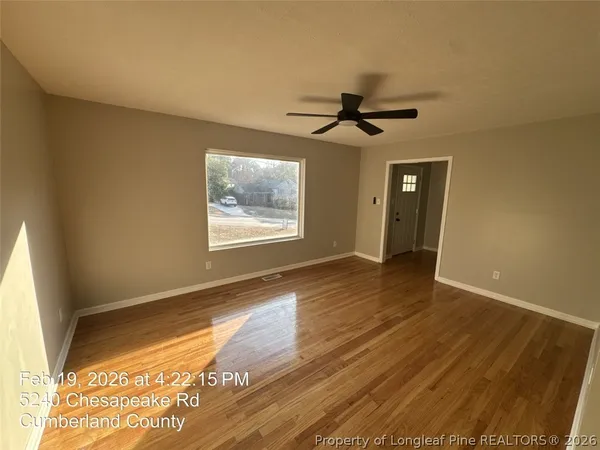 a view of empty room with wooden floor and fan