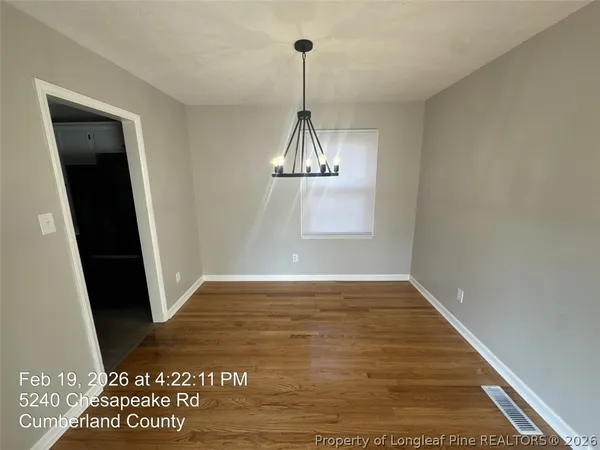 an empty room with wooden floor and window