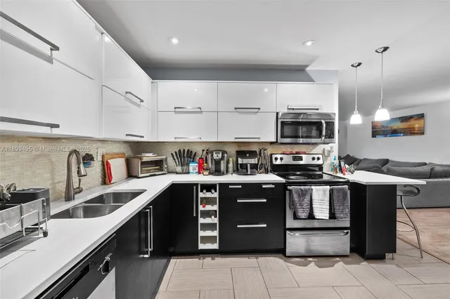 a kitchen with stainless steel appliances granite countertop a sink dishwasher a stove and a refrigerator with wooden floor