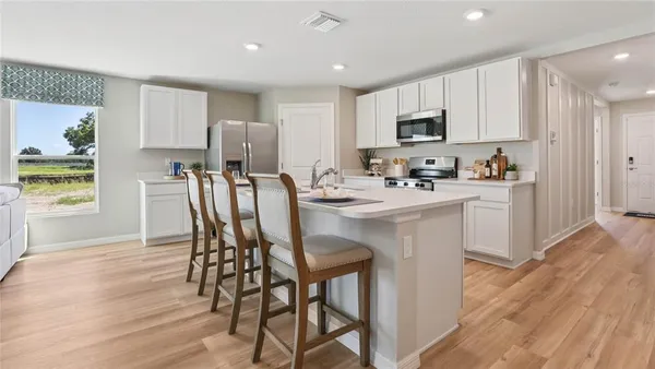 a kitchen with stainless steel appliances a microwave a sink a stove a table and chairs
