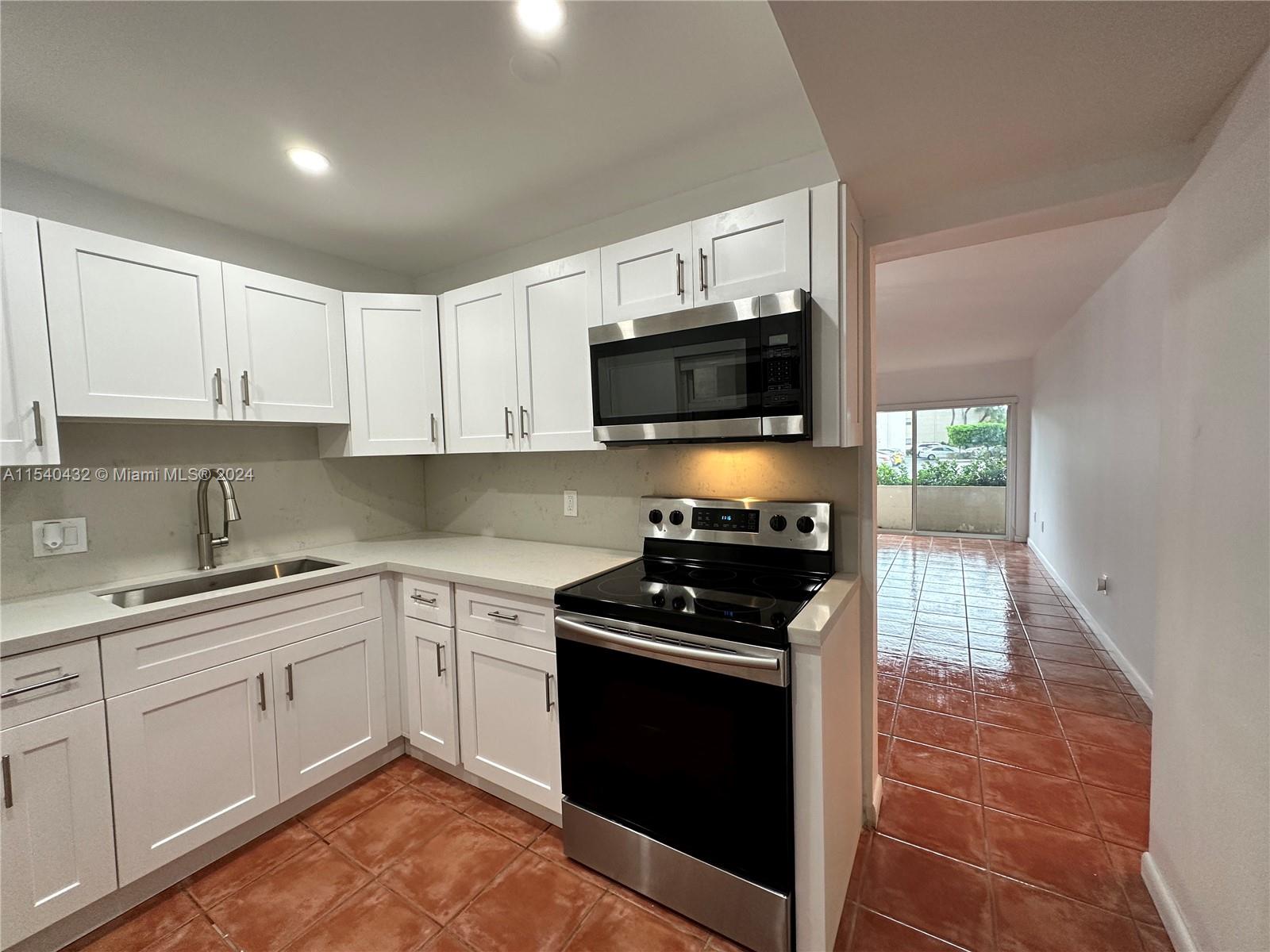 7785 Southwest 86th Street, Unit E116 Miami, FL 33143 - Photo 6 of 27 a kitchen with a sink stove top oven and cabinets