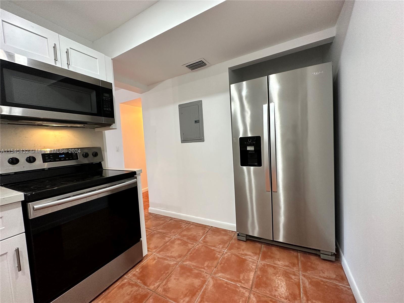 7785 Southwest 86th Street, Unit E116 Miami, FL 33143 - Photo 8 of 27 a view of kitchen with stove refrigerator and wooden floor
