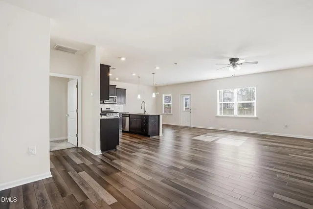 a view of an empty room with a kitchen and a window