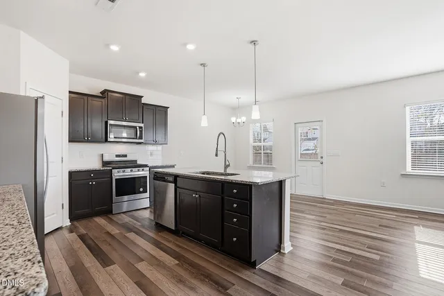 a open kitchen with stainless steel appliances granite countertop a stove a sink dishwasher a refrigerator and a oven with wooden floor