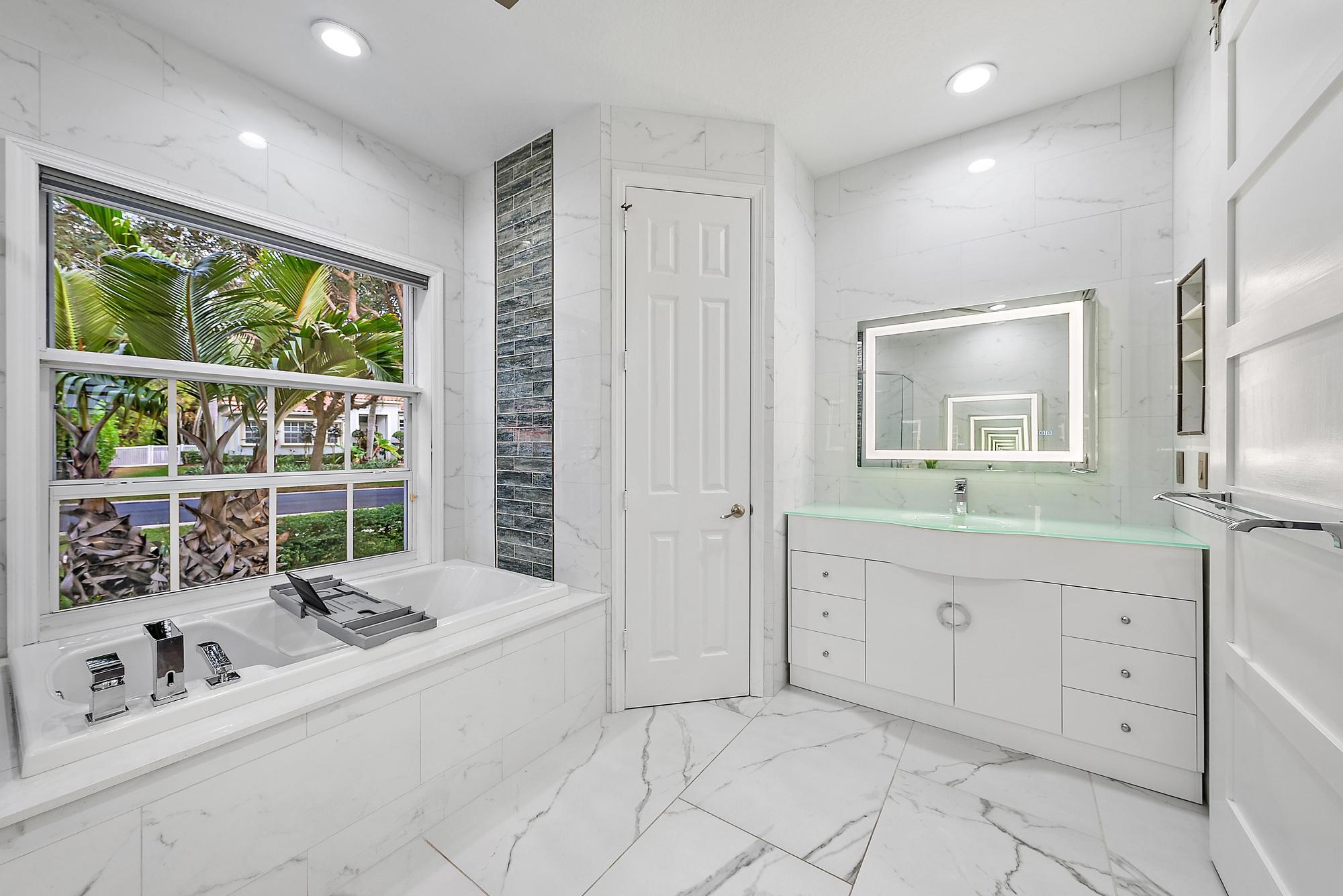 9790 Southeast Crape Myrtle Court Hobe Sound, FL 33455 - Photo 19 of 74 a spacious bathroom with a double vanity sink large mirror and a bathtub