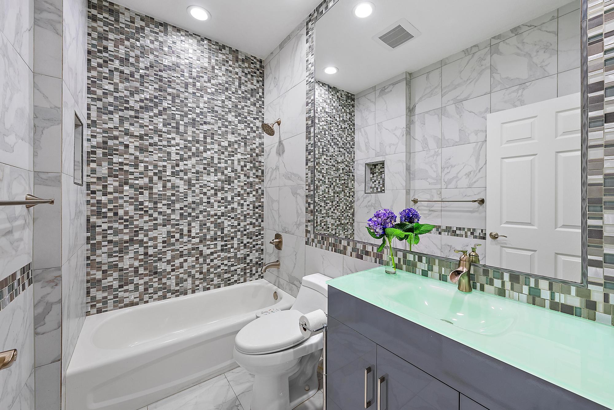 9790 Southeast Crape Myrtle Court Hobe Sound, FL 33455 - Photo 23 of 74 a bathroom with a granite countertop bathtub sink vanity mirror and toilet