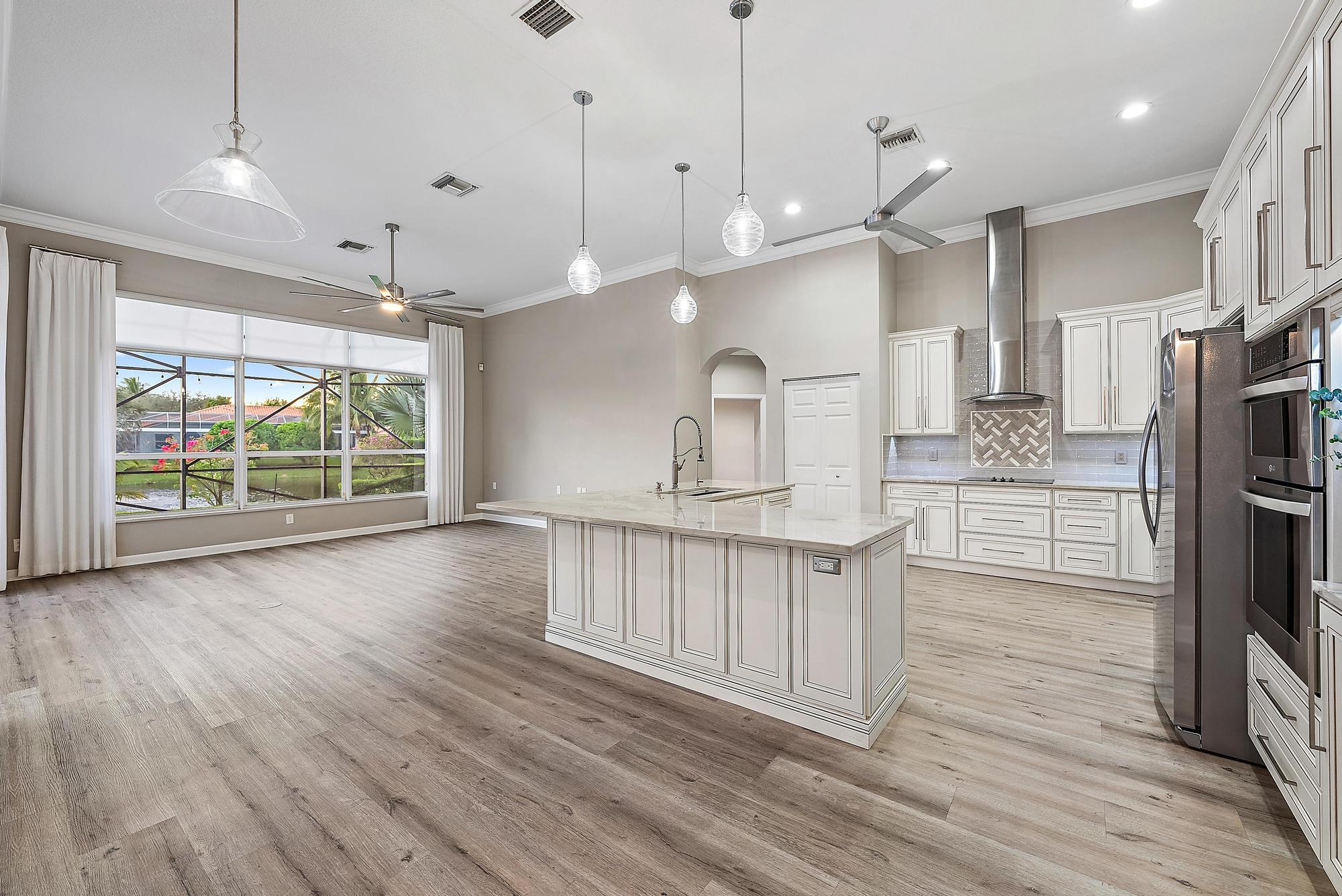 9790 Southeast Crape Myrtle Court Hobe Sound, FL 33455 - Photo 56 of 74 a open kitchen with stainless steel appliances granite countertop a refrigerator a oven a island a stove and a wooden floors