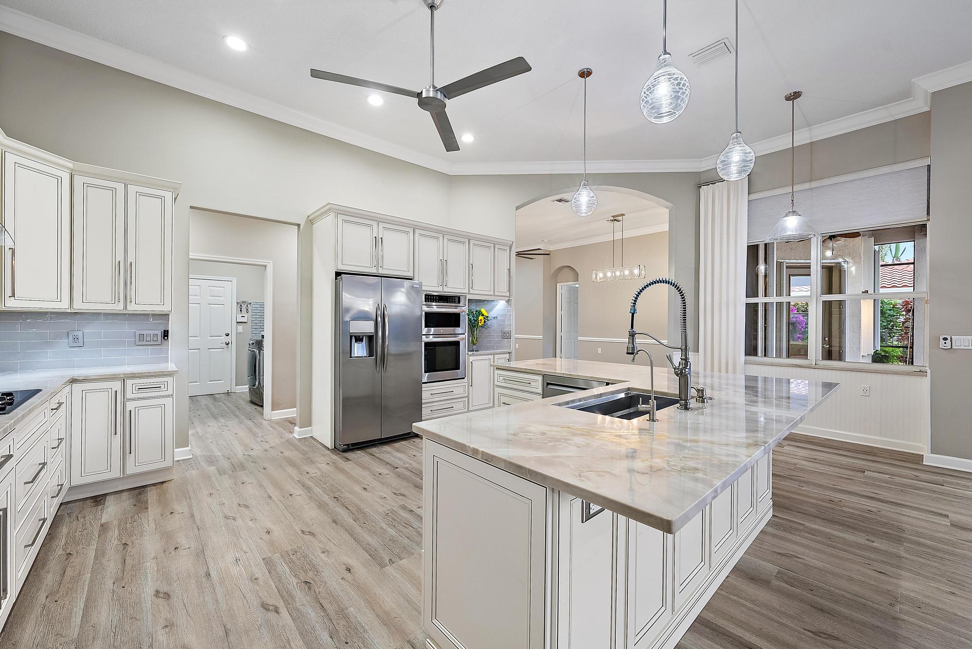 9790 Southeast Crape Myrtle Court Hobe Sound, FL 33455 - Photo 57 of 74 a kitchen with stainless steel appliances granite countertop a refrigerator a sink dishwasher a stove and white cabinets with wooden floor