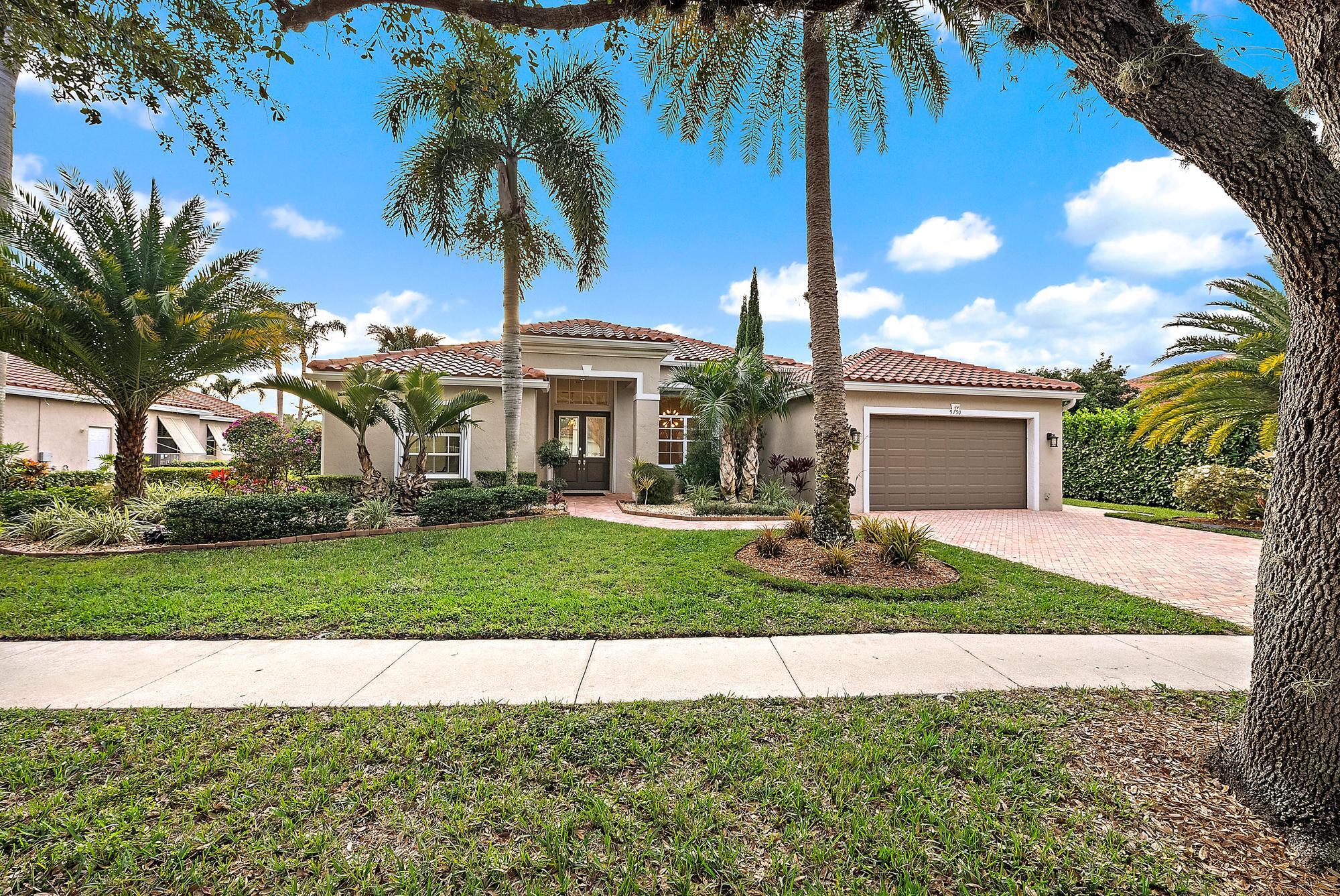9790 Southeast Crape Myrtle Court Hobe Sound, FL 33455 - Photo 9 of 74 a front view of a house with a yard and garage
