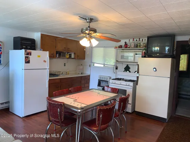 a kitchen with kitchen island a stove a refrigerator and a dining table with wooden floor