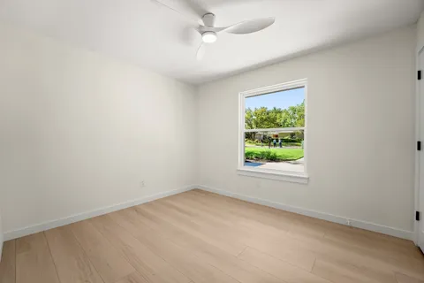 an empty room with a window and a ceiling fan
