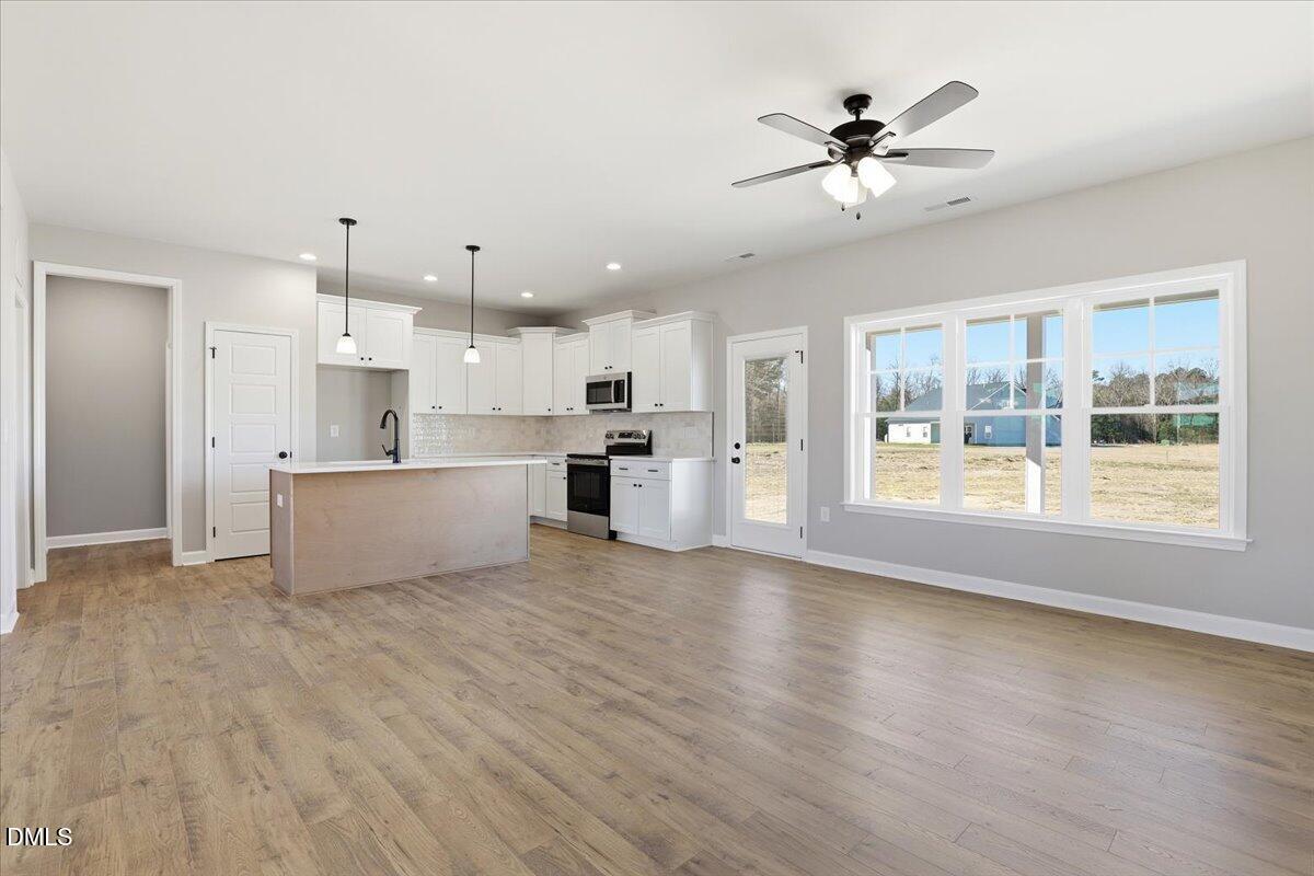 3696 Drew Farmer Road La Grange, NC 28551 - Photo 8 of 35 a view of a kitchen with a stove cabinets a ceiling fan and wooden floor
