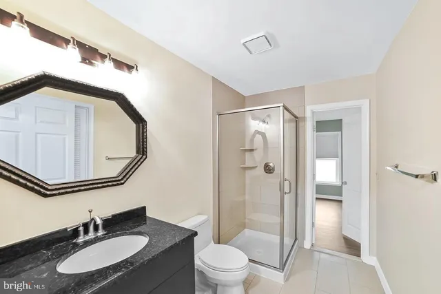 a bathroom with a granite countertop sink mirror toilet and shower