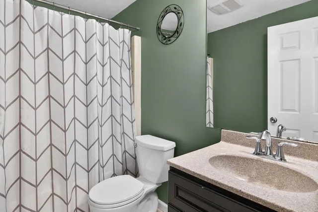a bathroom with a granite countertop toilet sink and mirror