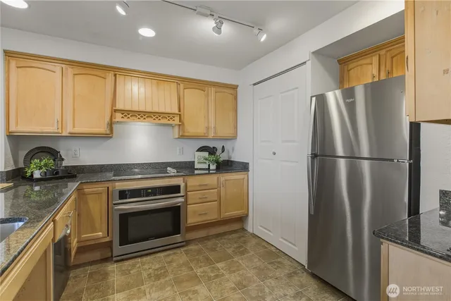a kitchen with stainless steel appliances granite countertop a refrigerator sink and stove