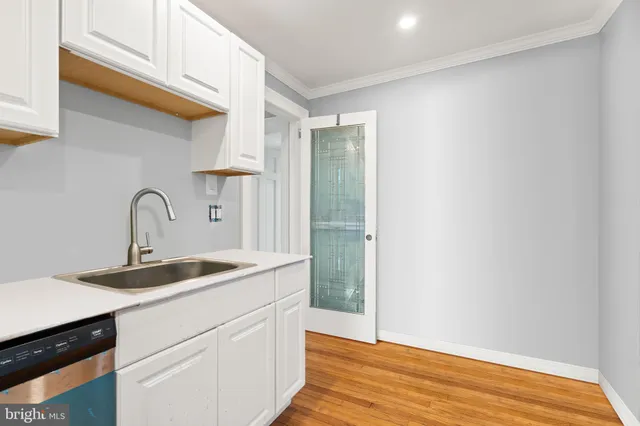 a close view of a sink and dishwasher with wooden floor