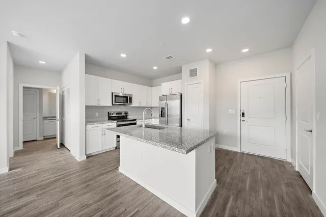 a kitchen with stainless steel appliances granite countertop a refrigerator and a stove top oven