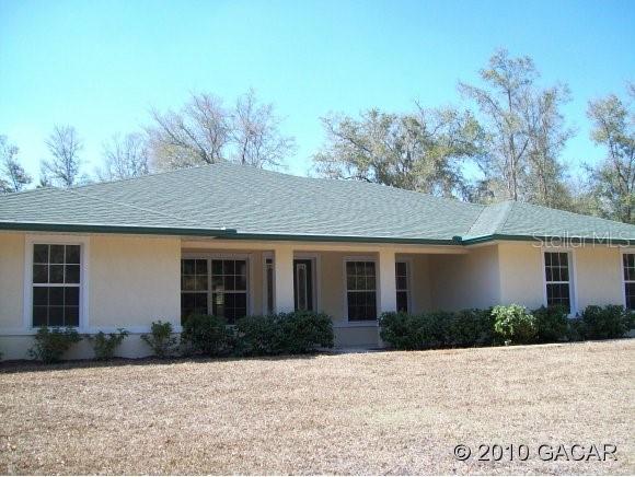2857 Northeast County Road High Springs, FL 32643 - Photo 1 of 1 a front view of house with yard and trees in the background