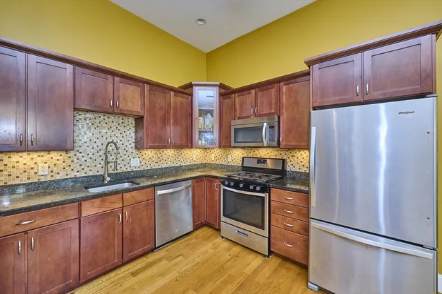 a kitchen with stainless steel appliances granite countertop wooden cabinets stove top oven and granite counter top