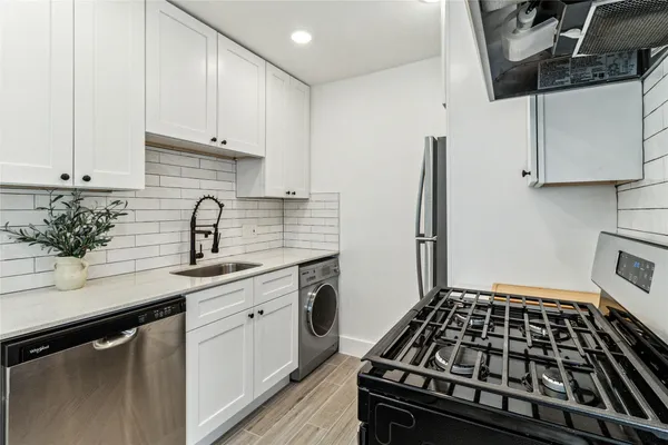 a kitchen with white cabinets a sink stove and refrigerator