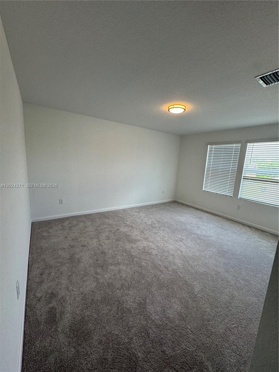 693 Carlyle Way Fort Pierce, FL 34947 - Photo 13 of 19 an empty room with a chandelier fan and windows