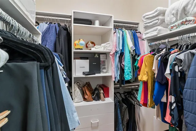 a view of walk in closet with clothes and shoes