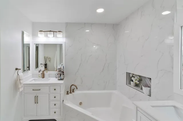 a bathroom with a bathtub shower sink and mirror
