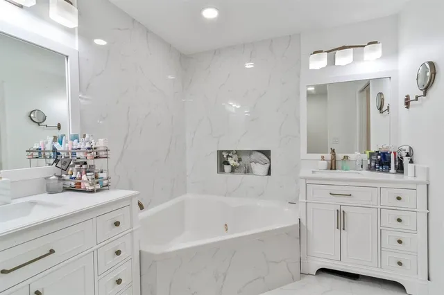 a bathroom with a double vanity sink mirror and bathtub