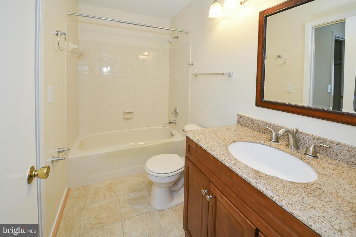11743 Summerchase Circle, Unit B Reston, VA 20194 - Photo 18 of 24 a bathroom with a granite countertop sink toilet mirror and bathtub