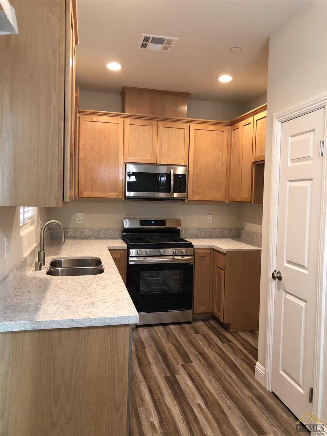 Undisclosed Address Wasco, CA 93280 - Photo 3 of 9 a kitchen with kitchen island granite countertop a sink and a stove top oven with wooden floor