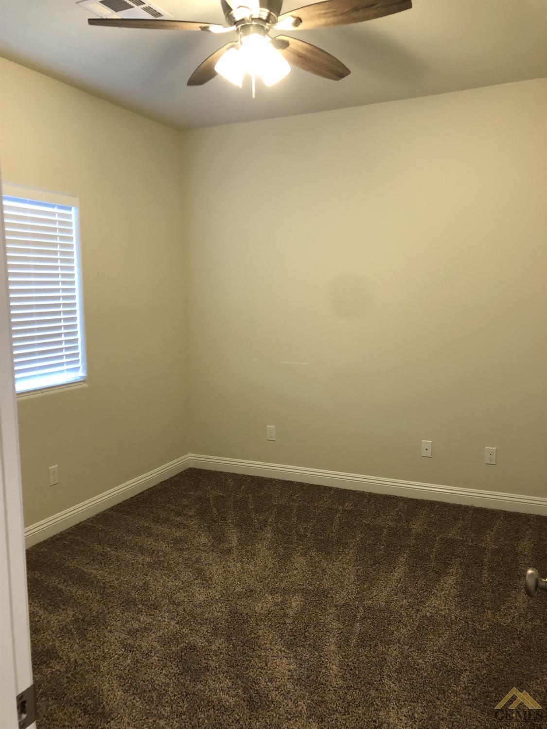 Undisclosed Address Wasco, CA 93280 - Photo 9 of 9 an empty room with a chandelier fan and window